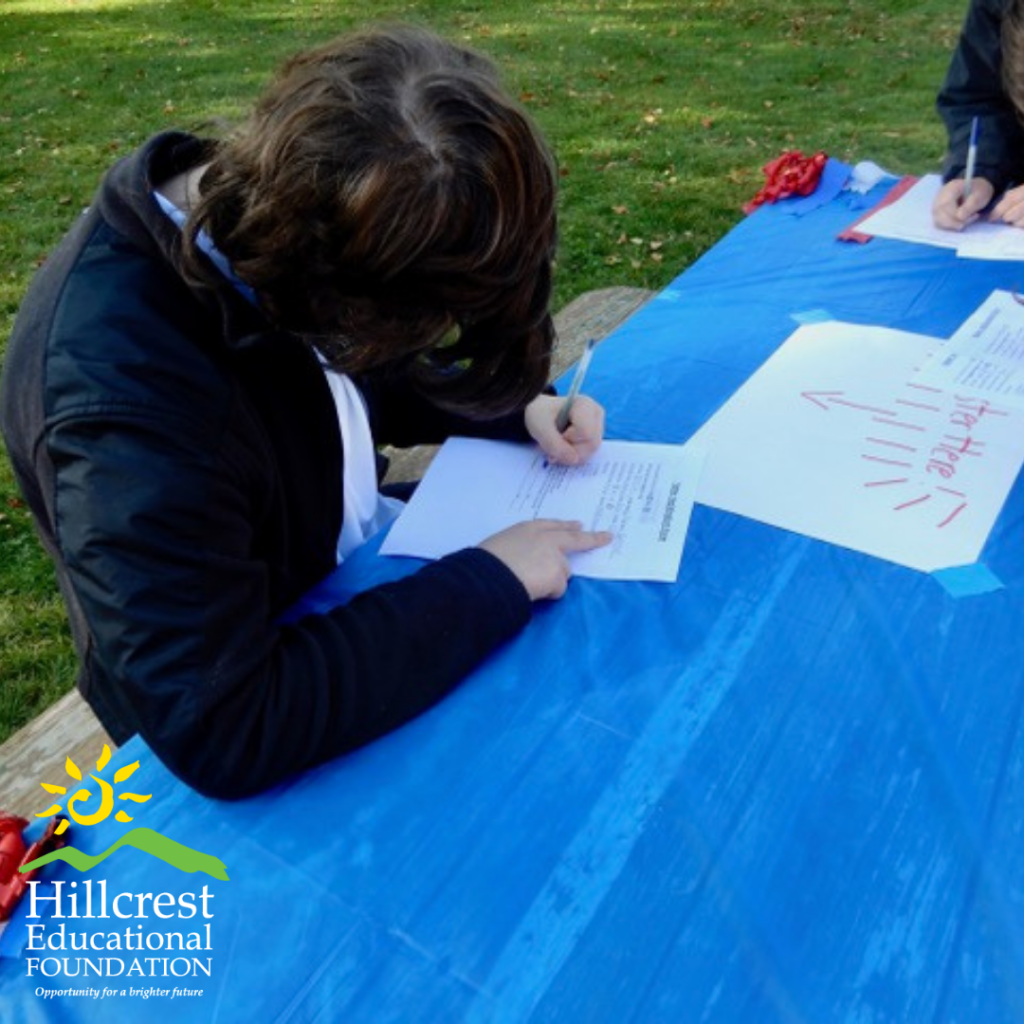 A student sits at the picnic table to fill out their registration form.